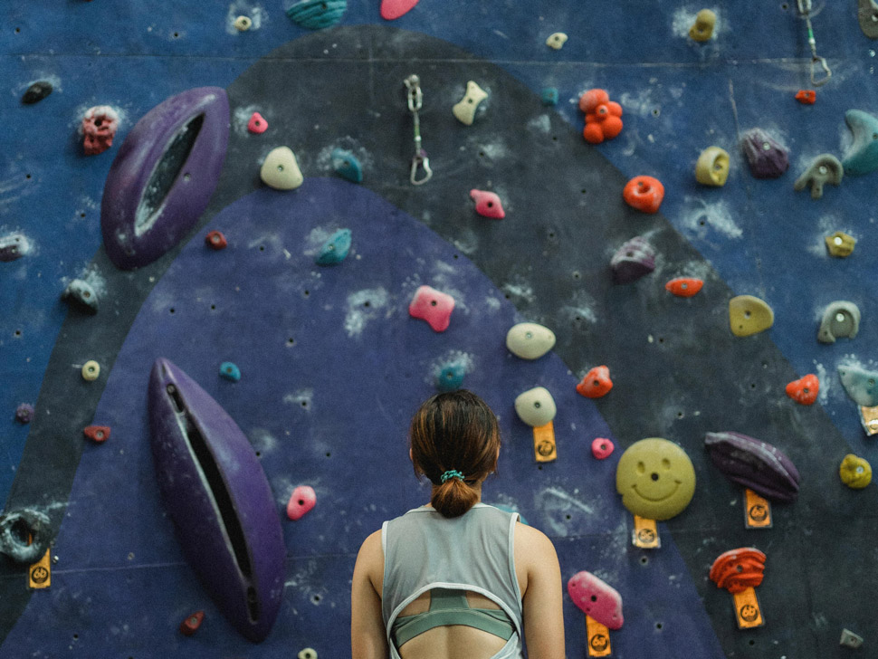 Woman staring at the intimidating rock climbing wall in front of her